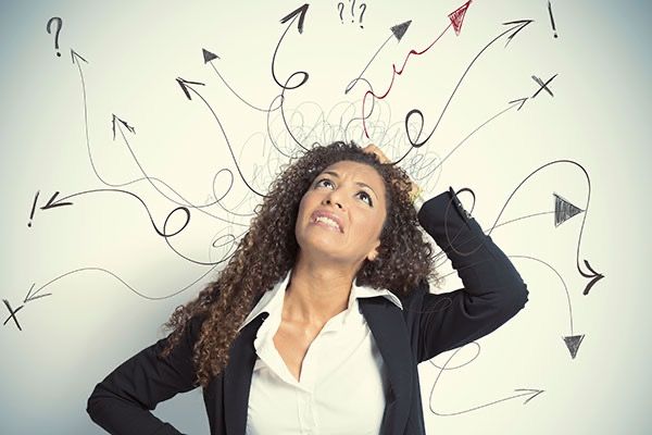 Confused businesswoman with arrows and question marks around her head.