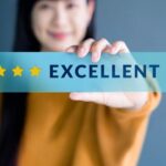 Person holding a blue card with a five-star rating and the word 'EXCELLENT'.