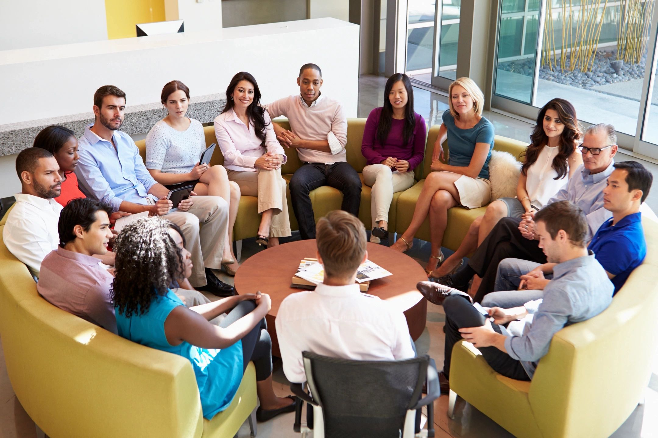 A diverse group of people engaged in a meeting around a coffee table.