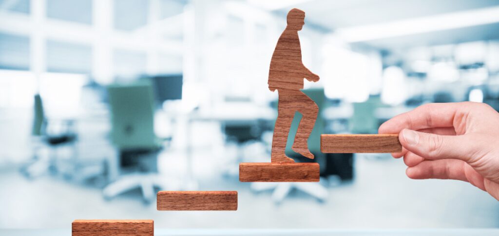 growth-mindset-marketing-ebccoaching A paper cutout figure climbing upward on brick-like steps.