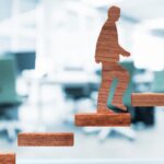 A paper cutout figure climbing upward on brick-like steps.
