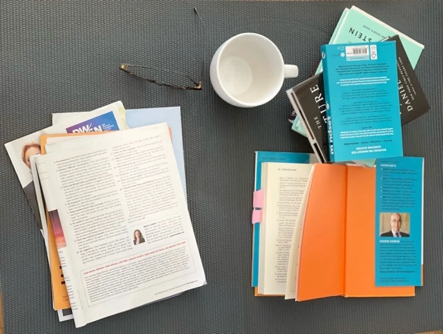 A workspace with documents, a coffee cup, and an orange folder.